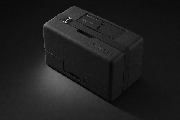 The new hard-foam packaging with the Meticulous strap, on a dark background.